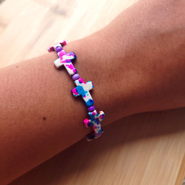 Pulsera de cruces con tonos azules, rosados, blancos y violetas.